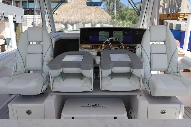 Slide: The Image of 2022 Regal 38 SAV boat cockpit with dual white captain chairs and advanced navigation system. - 57