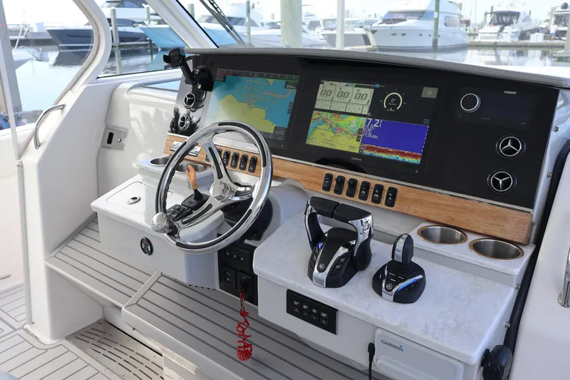 Slide: The Image of 2022 Regal 38 SAV boat helm with advanced navigation displays and controls at marina. - 63
