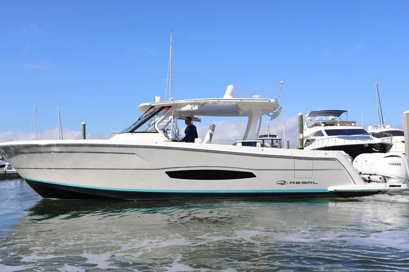 Slide: The Image of 2022 Regal 38 SAV boat docked in marina, clear blue sky background. - 7