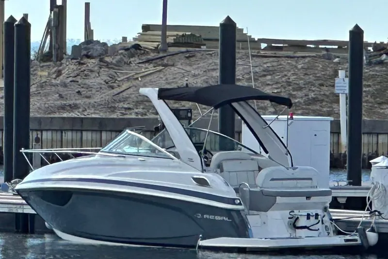The Image of 2022 Regal 28 Express boat docked at a marina with a black canopy. - 1