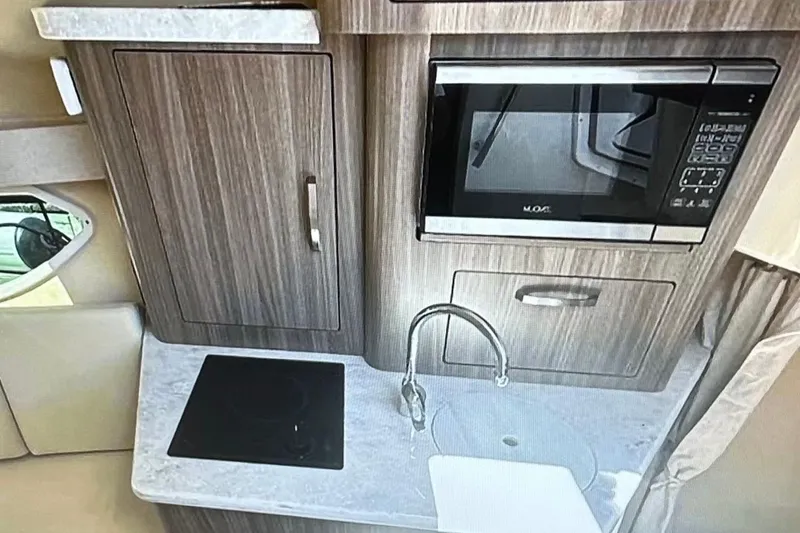 Slide: The Image of 2022 Regal 28 Express boat kitchen with microwave, sink, and stove. - 14