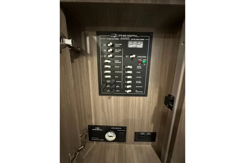 Slide: The Image of Control panel inside 2022 Regal 28 Express boat, featuring switches and level monitor. - 19