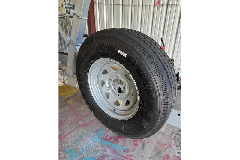 Slide: The Image of Trailer tire on a 2022 Regal 28 Express boat trailer, parked indoors. - 22