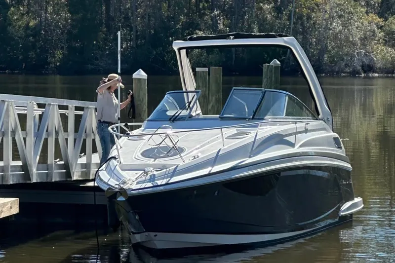 Slide: The Image of 2022 Regal 28 Express boat docked on a calm lake with a person securing it. - 3