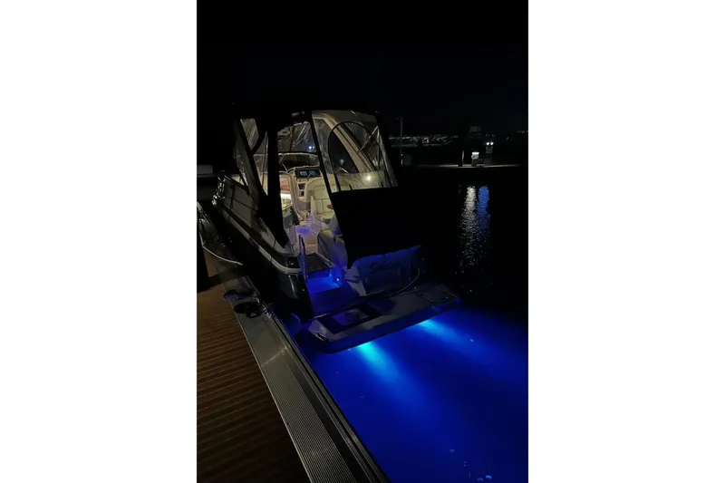 Slide: The Image of 2022 Regal 28 Express boat with illuminated deck at night, docked by the water. - 4