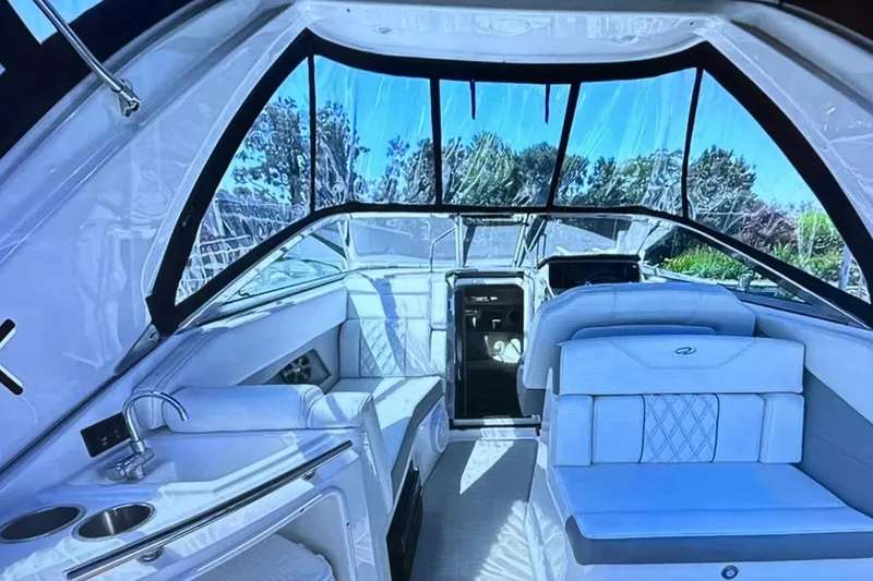 Slide: The Image of 2022 Regal 28 Express boat interior with seating and kitchenette, featuring clear canopy windows. - 6