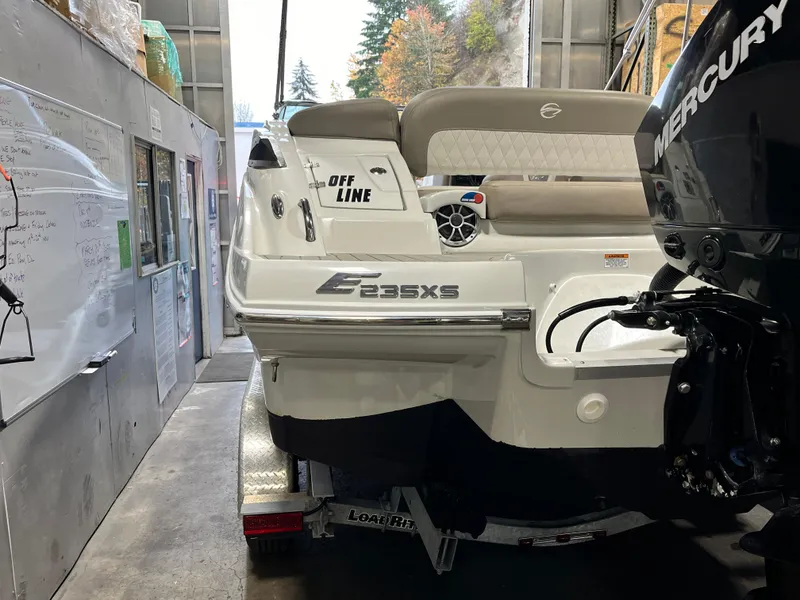 Slide: The Image of 2023 Crownline Eclipse E235 XS boat in a garage, featuring a Mercury engine. - 9