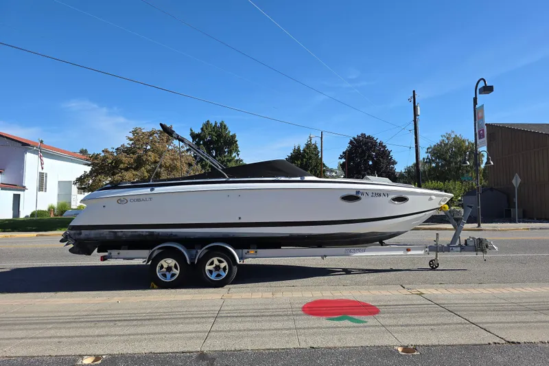 Slide: The Image of 2001 Cobalt 263 boat on trailer, parked on street under clear blue sky. - 1
