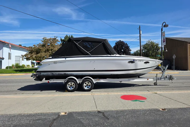 Slide: The Image of 2001 Cobalt 263 boat on trailer, parked on street, under clear blue sky. - 3