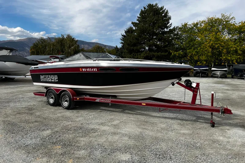 The Image of 1988 Mirage Manufacturing 217 Intruder boat on red trailer, parked outdoors. - 0
