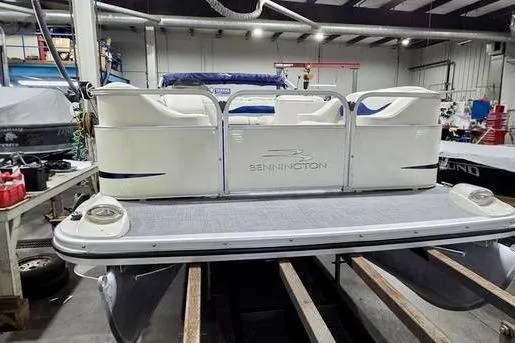 Slide: The Image of 2005 Bennington 205L pontoon boat parked outside blue garage doors. - 2
