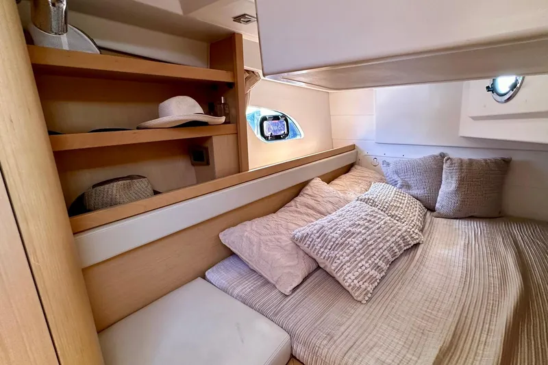 Slide: The Image of Cozy cabin interior of 2012 Beneteau Gran Turismo 34 with plush bedding and wooden shelves. - 33