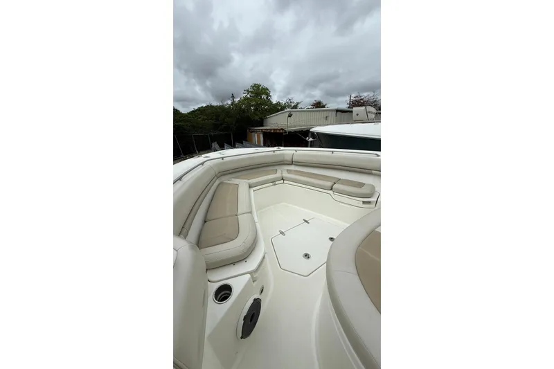 Slide: The Image of 2022 Boston Whaler 380 Outrage boat interior with cushioned seating under cloudy sky. - 12