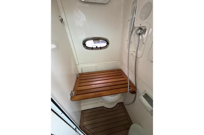 Slide: The Image of 2022 Boston Whaler 380 Outrage bathroom with wooden seat and showerhead. - 7