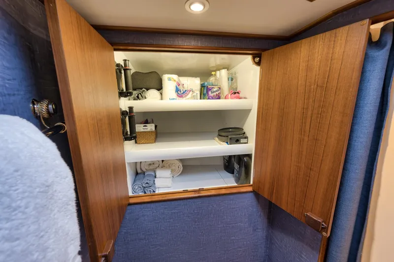 Slide: The Image of Wooden cabinet with open doors revealing neatly organized shelves in a 1997 Merritt 58. - 144