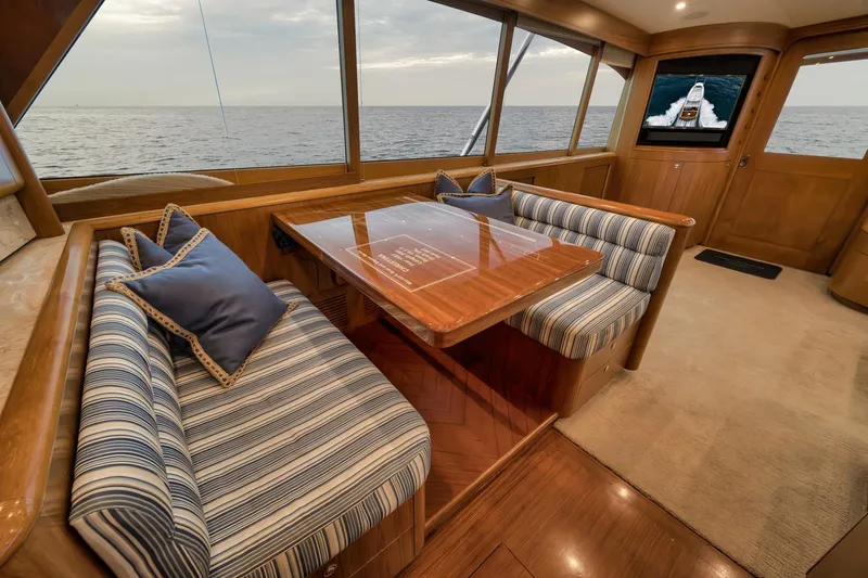 Slide: The Image of Luxurious Merritt 58 yacht interior with striped seating, wooden table, and ocean view, 1997 model. - 127