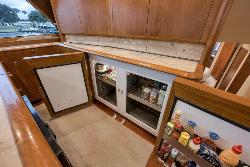 Slide: The Image of Interior of a 1997 Merritt 58 yacht kitchen with open cabinets and various condiments. - 136