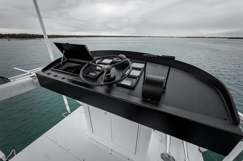 Slide: The Image of Helm of 1997 Merritt 58 yacht with steering wheel and controls, overlooking calm waters. - 47