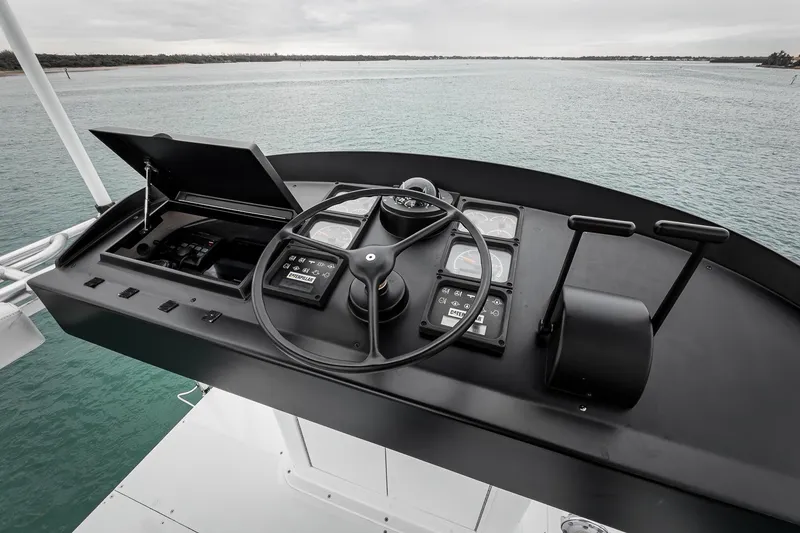 Slide: The Image of Helm of 1997 Merritt 58 yacht with steering wheel and controls, overlooking calm waters. - 48