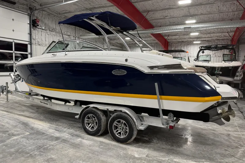 Slide: The Image of 2012 Cobalt 276 boat with blue and yellow accents on a trailer in a garage. - 3