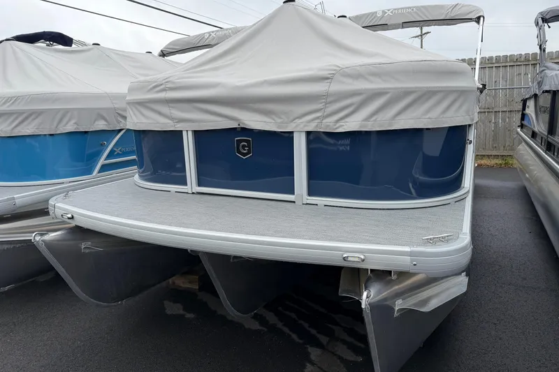 Slide: The Image of 2026 Godfrey EX2286SBX pontoon boat with protective cover, parked outdoors. - 11