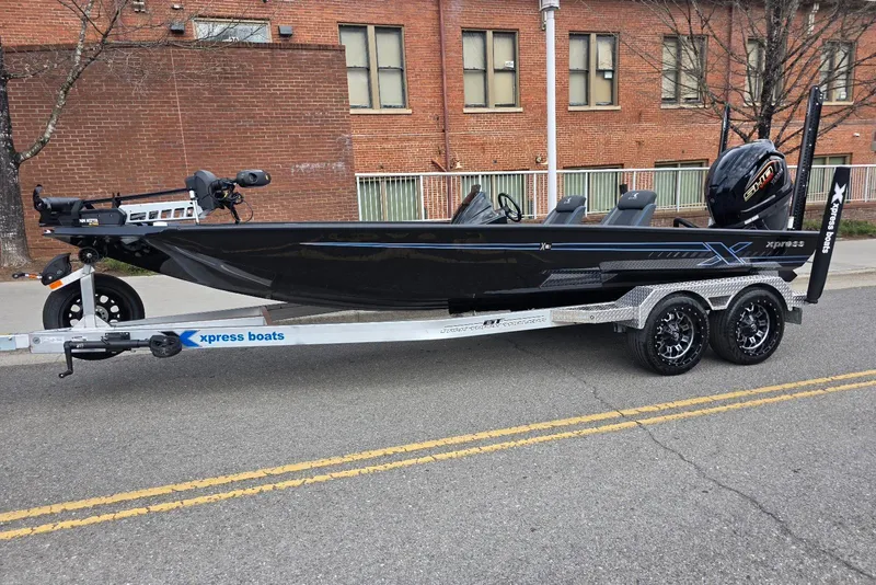 The Image of 2026 Xpress X21 Pro boat on trailer, parked on street, with brick building background. - 8