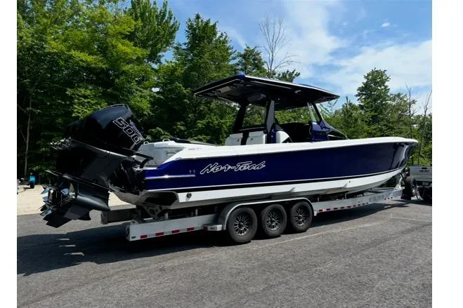 Slide: The Image of 2024 Nor-Tech 400 Supersport boat on trailer, parked outdoors with trees in background. - 2