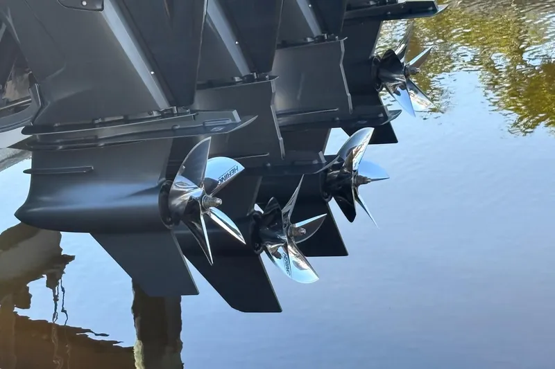 Slide: The Image of 2024 Nor-Tech 400 Supersport boat propellers reflecting on calm water. - 22