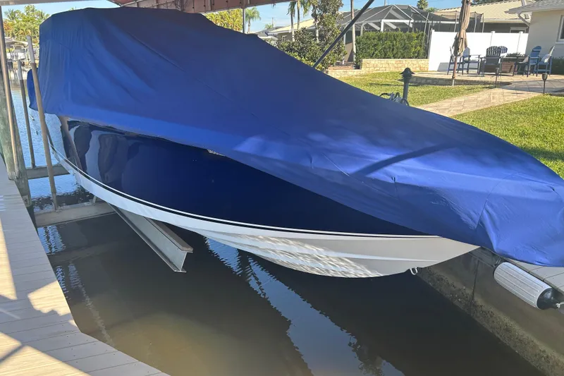 Slide: The Image of 2024 Nor-Tech 400 Supersport boat covered with a blue tarp, docked in a marina. - 23