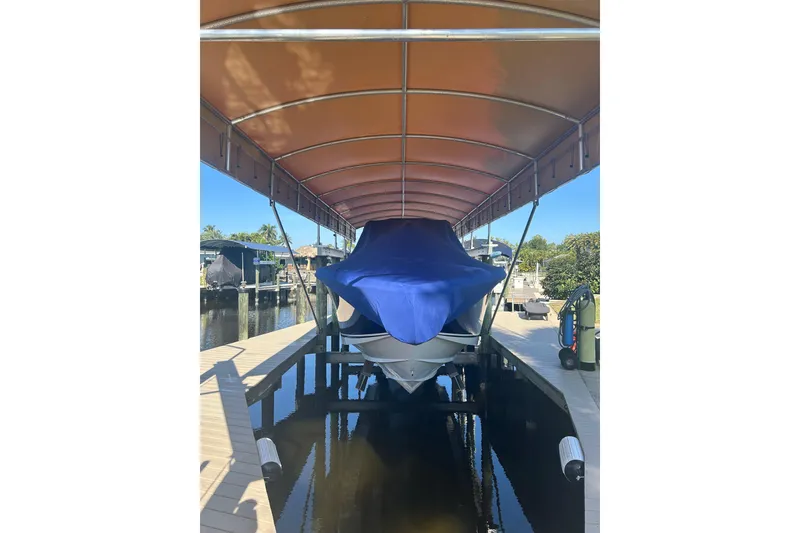 Slide: The Image of 2024 Nor-Tech 400 Supersport boat covered in blue tarp under dock canopy. - 24