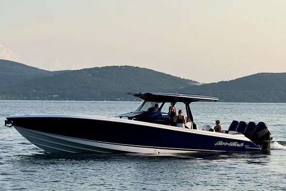 Slide: The Image of 2024 Nor-Tech 400 Supersport boat cruising on a serene lake with scenic mountain backdrop. - 3