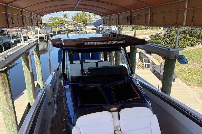 Slide: The Image of 2024 Nor-Tech 400 Supersport boat docked under canopy, showcasing sleek design and luxury seating. - 7