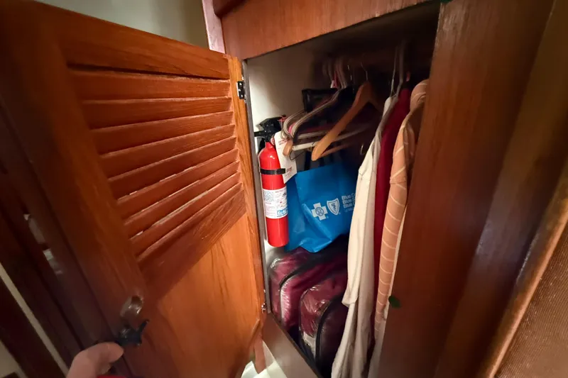 Slide: The Image of Wooden closet on 1979 O'Day 37 sailboat with clothes, fire extinguisher, and bags. - 17