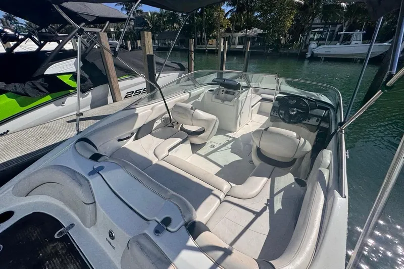 Slide: The Image of 2012 Yamaha Boats SX190 interior with seating and steering, docked by the water. - 11
