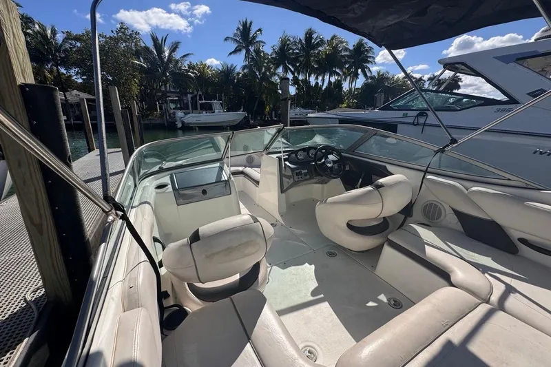 Slide: The Image of 2012 Yamaha Boats SX190 interior with seating, steering wheel, and dashboard, docked near palm trees. - 14