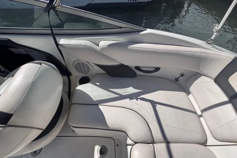 Slide: The Image of 2012 Yamaha Boats SX190 interior with white seating and cup holder, docked by water. - 16