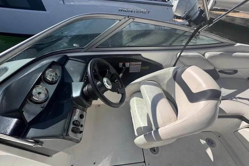 Slide: The Image of 2012 Yamaha Boats SX190 interior with steering wheel and gauges, docked near another boat. - 20