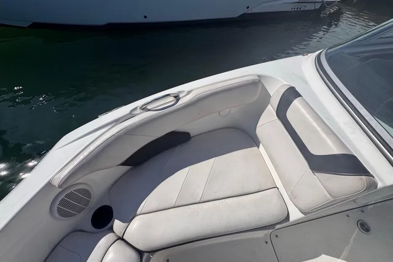 Slide: The Image of 2012 Yamaha Boats SX190 interior seating with cup holder and speaker, docked on water. - 28