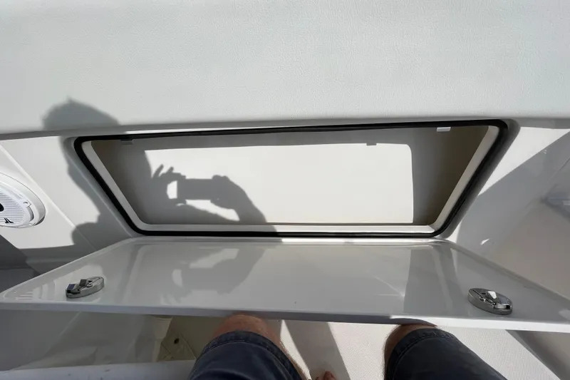Slide: The Image of 2020 Jupiter 34 Center Console storage compartment with open hatch and shadow reflection. - 19