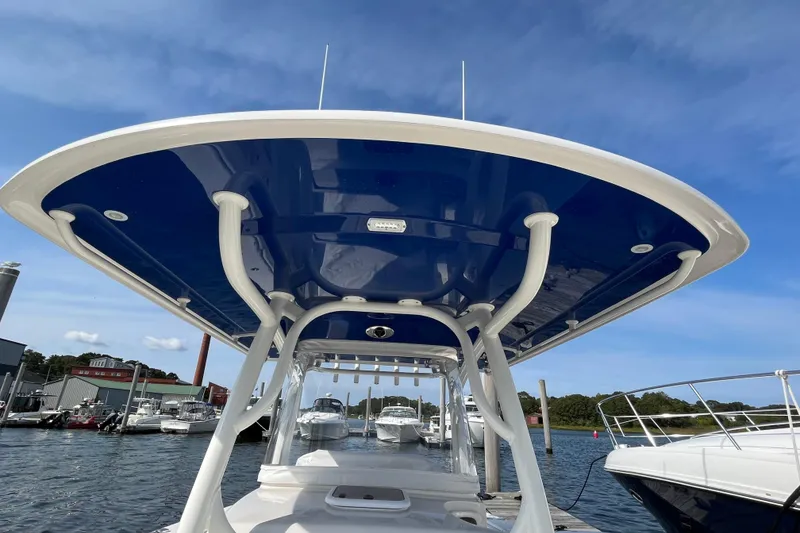 Slide: The Image of 2020 Jupiter 34 Center Console boat docked, showcasing sleek design and blue canopy. - 6