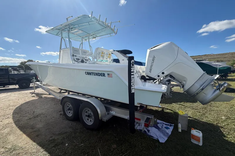 Slide: The Image of 2024 Contender 28 Tournament boat on trailer with Mercury outboard engine, parked outdoors. - 21