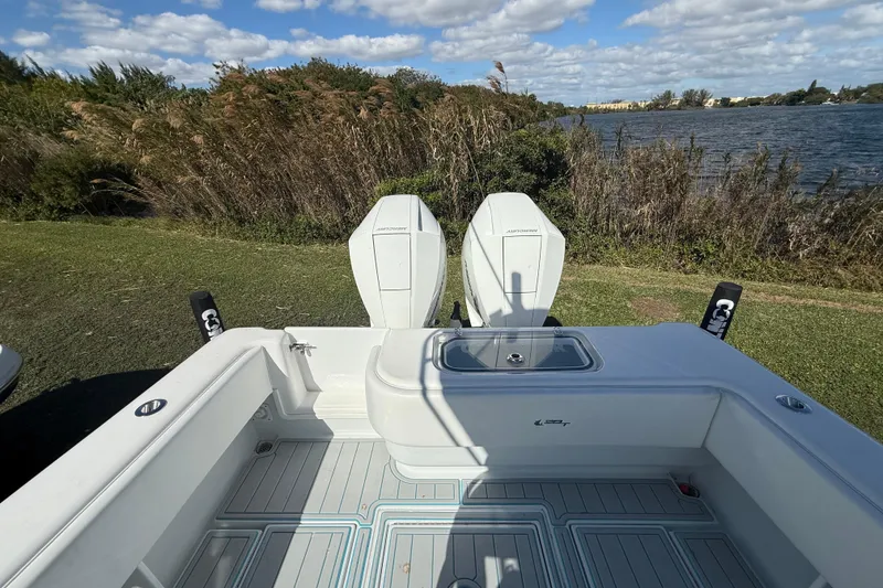 Slide: The Image of 2024 Contender 28 Tournament boat with twin engines, docked by a scenic lake. - 8