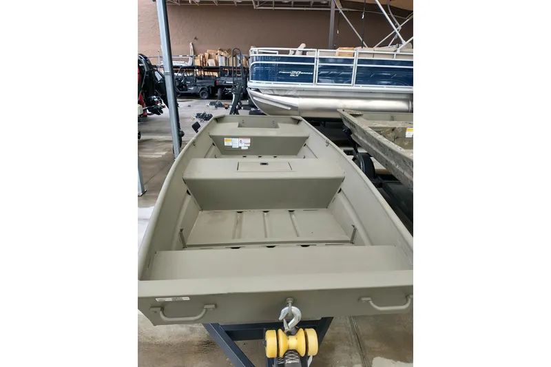 Slide: The Image of 2026 Tracker Grizzly 15 Jon boat in showroom, olive green, on trailer. - 2