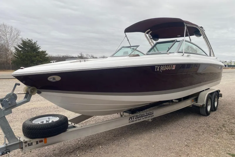 Slide: The Image of 2008 Cobalt 272 boat on trailer, parked outdoors under cloudy sky. - 2