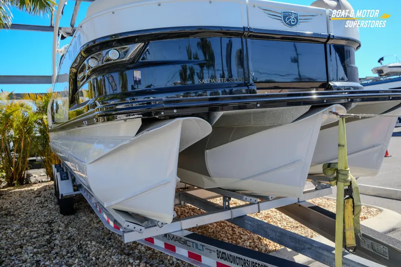 Slide: The Image of 2024 Avalon Twin Quad Lounger Windshield boat on trailer, rear view, sunny day. - 12