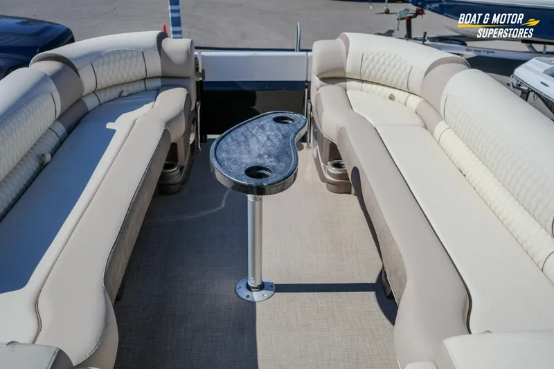 Slide: The Image of 2024 Avalon Twin Quad Lounger Windshield boat interior with plush seating and central table. - 32