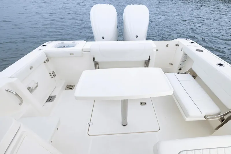 Slide: The Image of 2026 Pursuit DC 286 Dual Console boat interior with seating and table on water. - 4