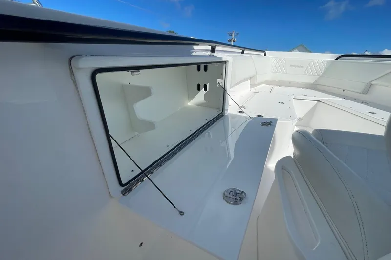 Slide: The Image of 2022 Everglades 335 Center Console boat interior storage compartment, open under clear blue sky. - 10