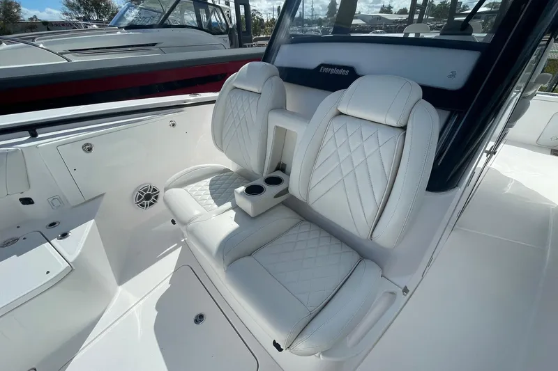 Slide: The Image of 2022 Everglades 335 Center Console boat interior with white leather seating and cup holders. - 16