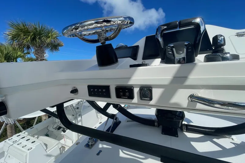 Slide: The Image of 2022 Everglades 335 Center Console helm with controls, steering wheel, and clear blue sky. - 19